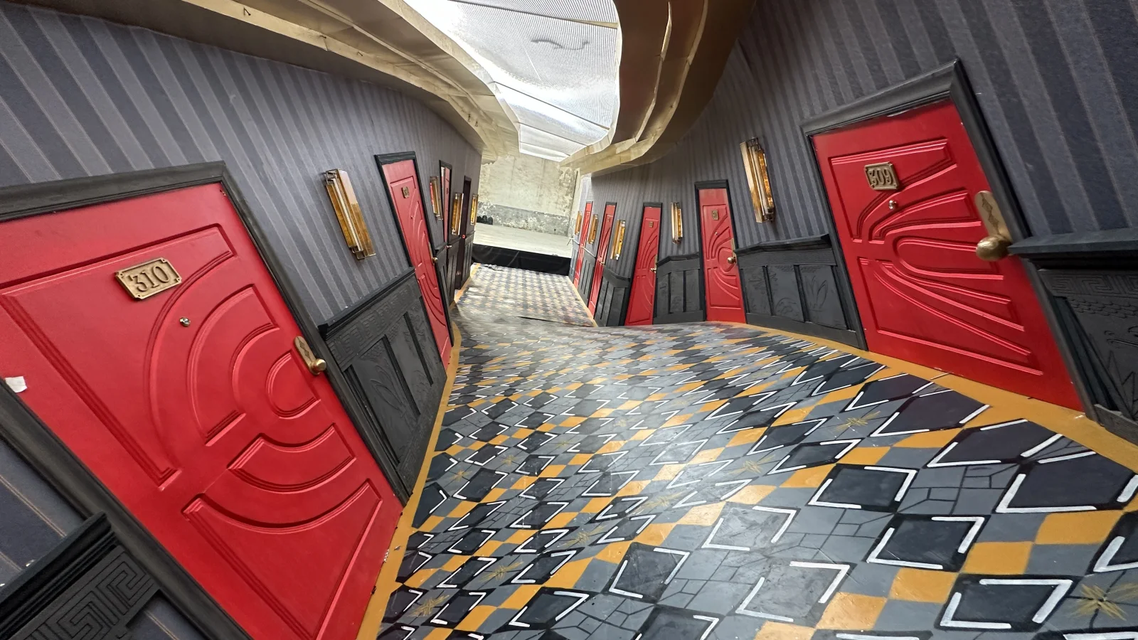 SUERTE — The corridor of red doors, dry: the diamond floor and the brass sconces