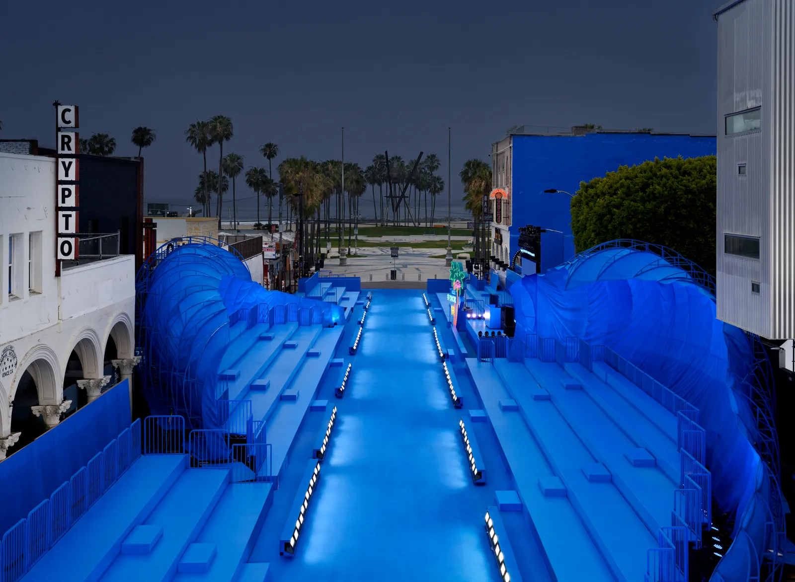 DIOR HOMME — The blue runway from above, between the two waves and the bleachers, the beach beyond