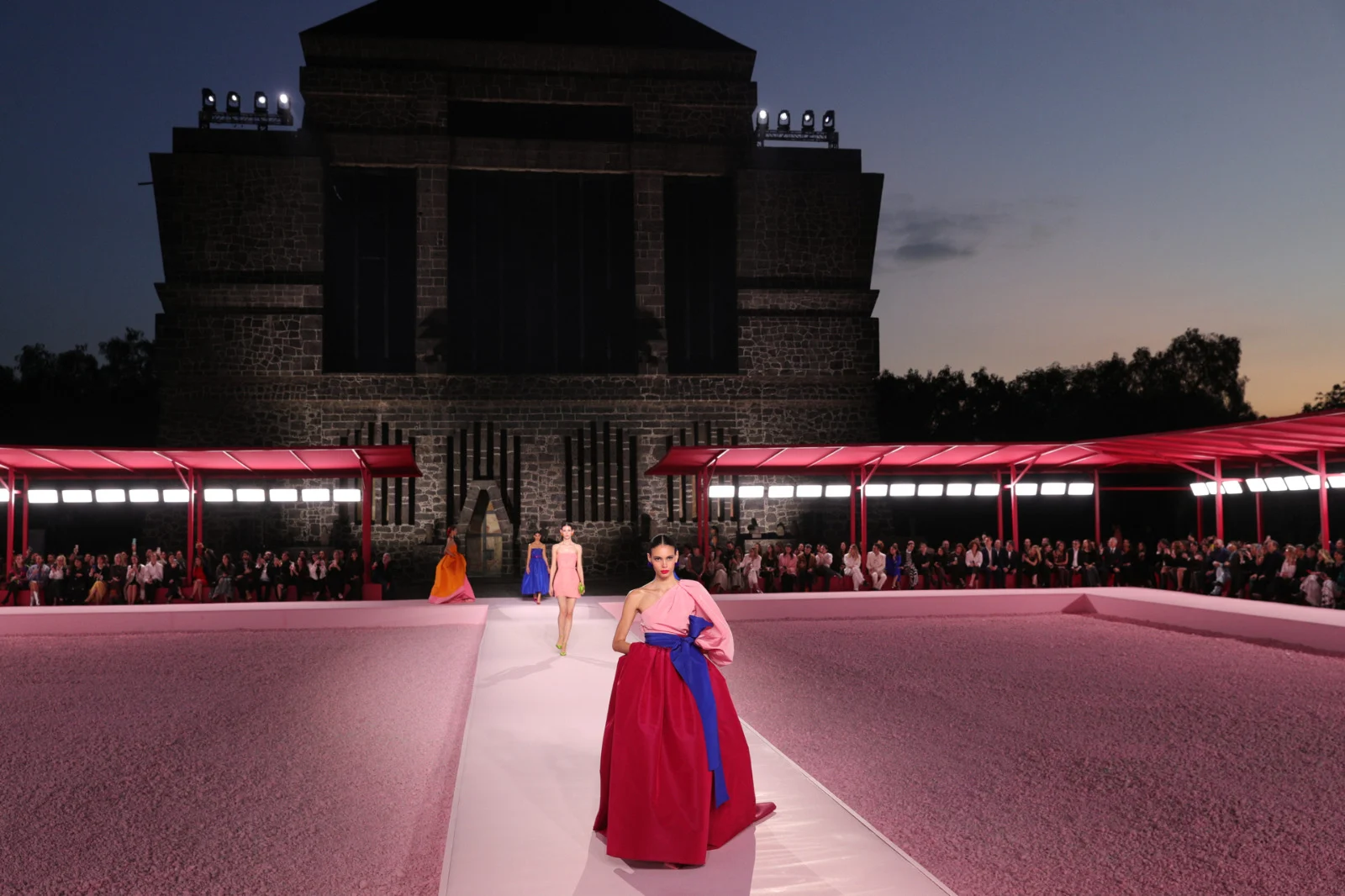 CAROLINA HERRERA — The red and blue gown on the pink runway, the Anahuacalli behind