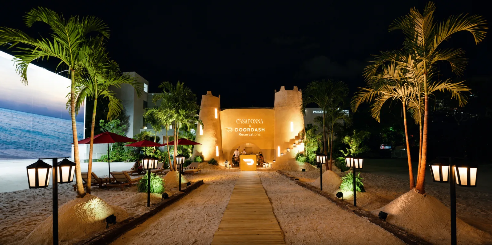 DOORDASH — The castle at night, the sea behind and the palms lit up
