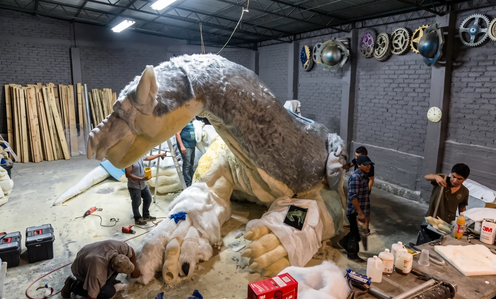 DISNEY — The workshop: the dragon half-covered in fur, the crew around it