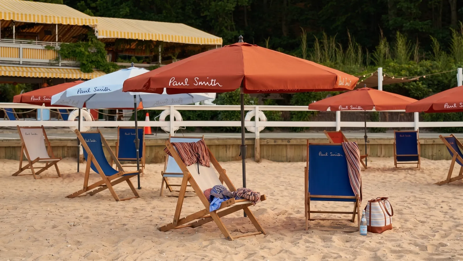 PAUL SMITH — The beach: Paul Smith chairs and umbrellas, the striped house behind
